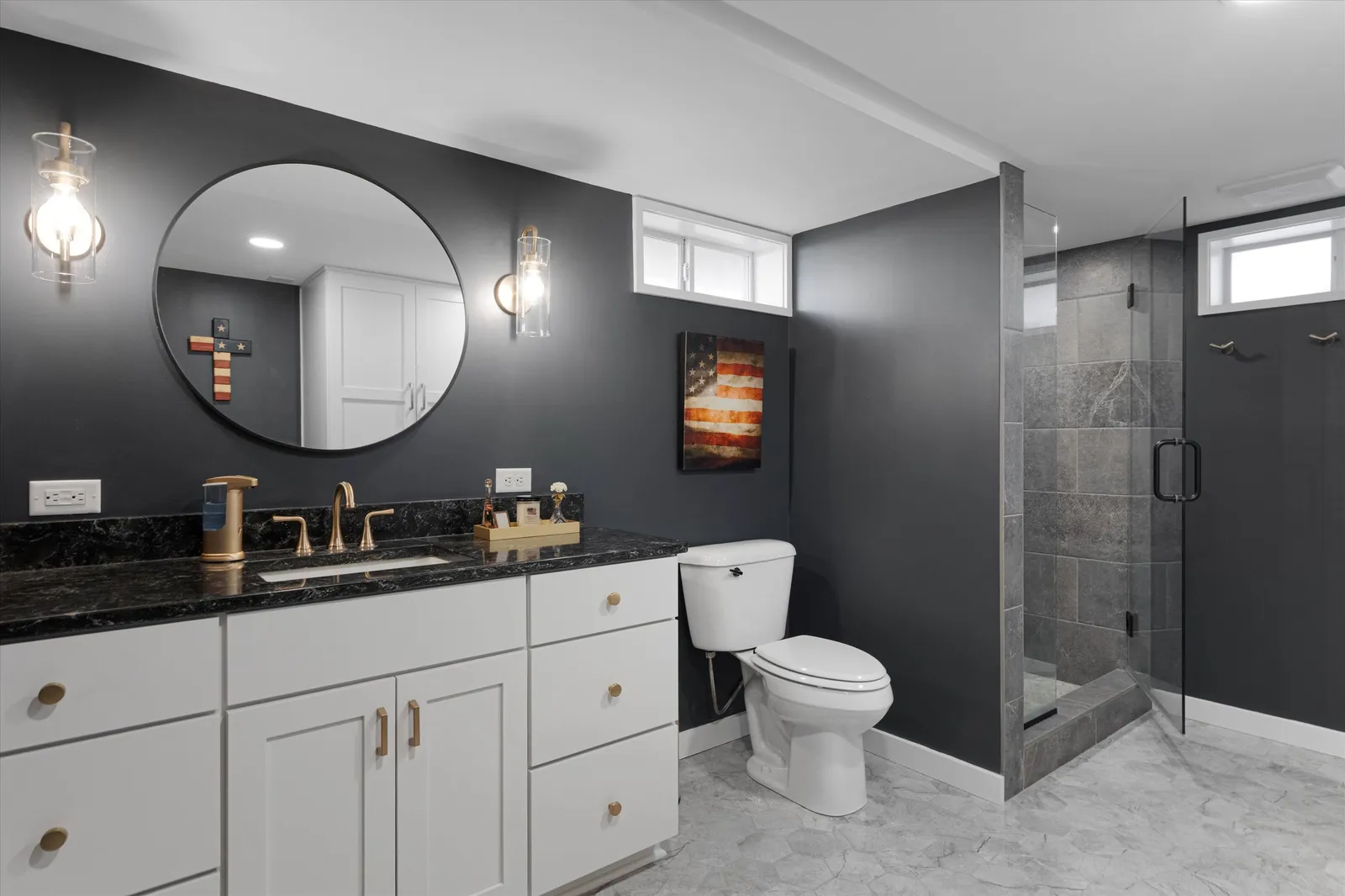 Bathroom remodel with charcoal walls, round mirror, and glass walk-in shower