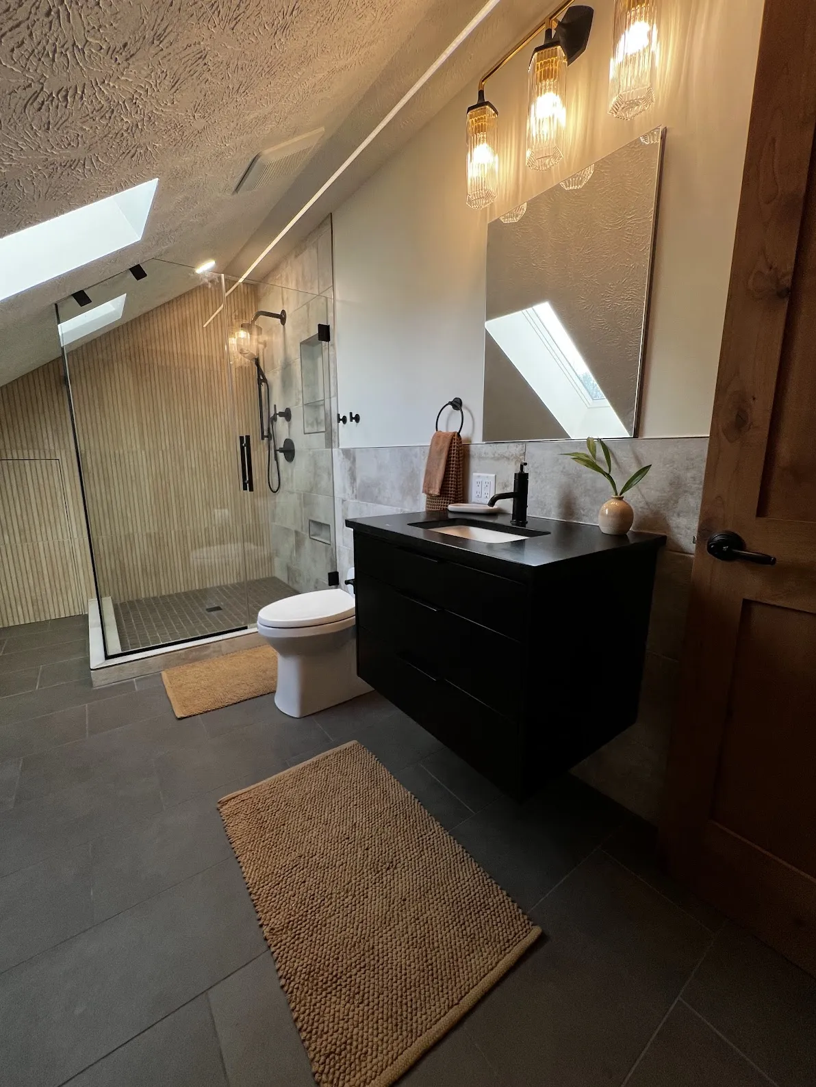 Bathroom remodel with skylight, floating vanity, and frameless glass shower